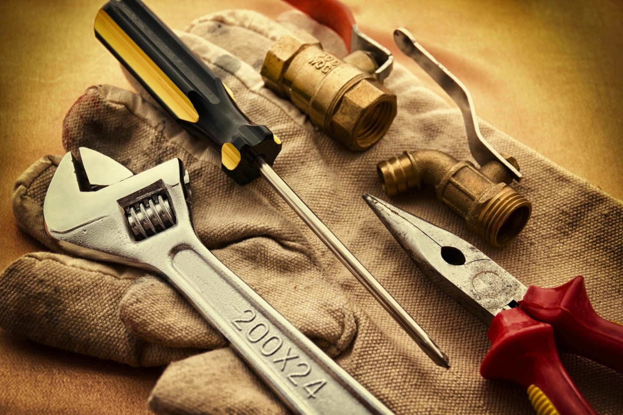 Plumbing tools laid on a work glove